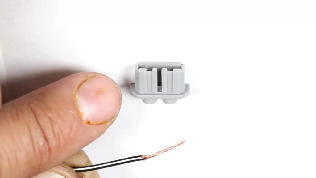 Fit the black wire with the white stripe into the hole on the left-hand side